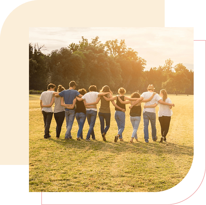 A group of people standing in the grass with their hands around each other.